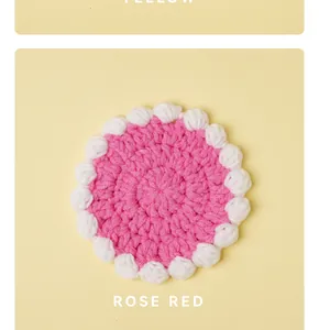 Macro detail of a handmade crochet rose red and white cream style round yarn coaster.