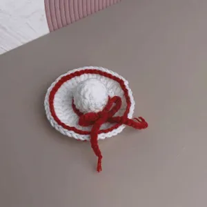 Close-up detail of a mini handmade crochet sun hat accessory for dolls, white and red