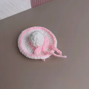 Close-up of a miniature pink and white handmade knitted doll sun hat