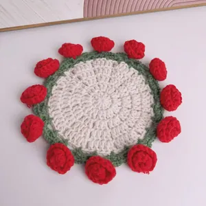 Primo piano di un sottobicchiere all'uncinetto fatto a mano con rose rosse e bordo verde