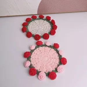 Vista dettagliata di due sottobicchieri all'uncinetto fatti a mano con rose rosa e bianche