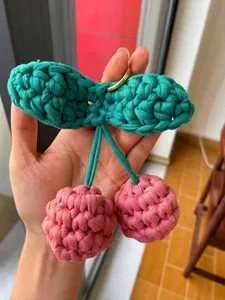 Dettaglio di un portachiavi a forma di ciliegia lavorato a mano all'uncinetto per auto o borsa