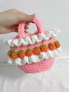 Close-up of pink crochet tote bag featuring white ruffles and small strawberry details