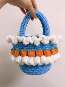 Close-up of handmade crochet basket with white ruffles and orange strawberries