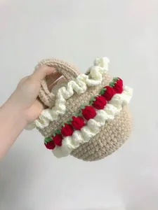 Detail view of a handmade crochet strawberry basket bag with ruffles held by hand