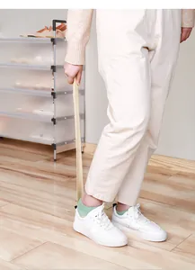 Demonstration of a long-handled shoehorn being used to put on white sneakers comfortably
