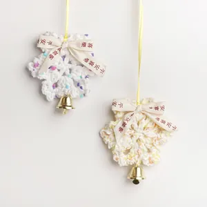 Handgefertigte Häkel-Schneeflocken-Ornamente mit goldenen Glocken und Dekobändern für Weihnachten.