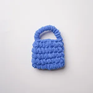 Vista detallada de una bolsa de ganchillo de chenilla azul con textura de punto artesanal