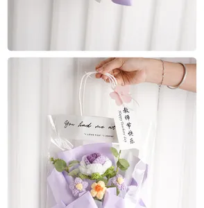 Hand holding a handmade crochet purple rose flower bouquet inside a clear gift bag