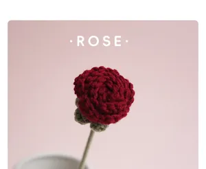Nahaufnahme einer handgestrickten roten Rose aus Wolle vor einem rosa Hintergrund
