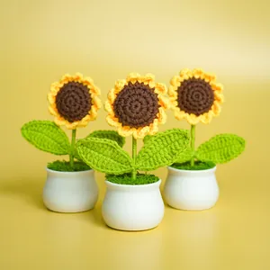 Three handmade crochet sunflower potted plants in small white ceramic vases.