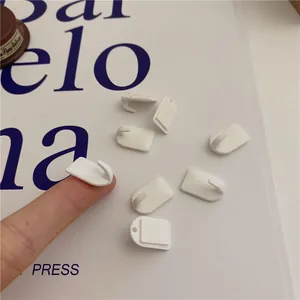 Mini white adhesive wall hooks for hanging jewelry and keys, compact sticky hangers.