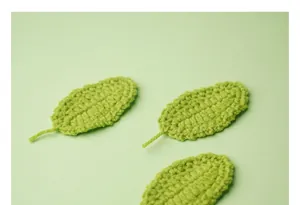 Primer plano de hojas verdes de ganchillo hechas a mano para decoración floral DIY y accesorios
