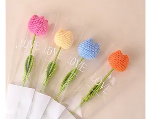 Close-up of four colorful handmade crochet tulip flowers in elegant gift packaging
