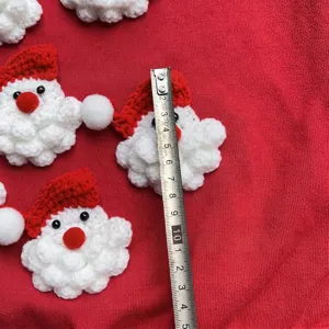 Detailed view of a handmade crocheted Santa Claus decoration with a measurement tape
