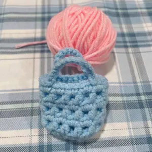 Detailansicht eines handgefertigten hellblauen Mini-Häkelbeutel-Anhängers mit Garntextur