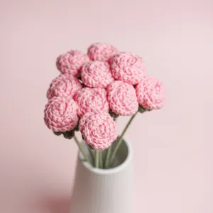 Eleganter handgehäkelter rosa Rosenstrauß, präsentiert in einer weißen Keramikvase