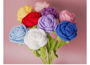 Handmade crochet rose bouquet detail, colorful wool knitted flowers with green leaves, close-up.