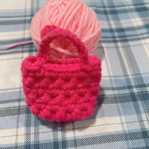Detailansicht eines handgefertigten rosa Häkel-Mini-Taschenanhängers mit Garnknäuel