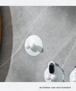 Close-up of white suction cup toothbrush holder hook on gray tile bathroom wall (85 chars)