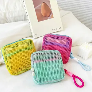 Three colorful square mesh cosmetic bags in yellow, pink and green on a white bed