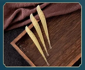 Detailed view of three feather-shaped translucent soft resin ear picks on a tray