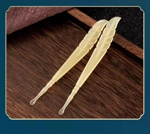 Detailed macro view of feather-shaped yellow ear picks on a wooden tray