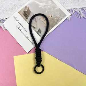 Detailopname van een zwarte gevlochten polsband met een matzwarte ronde metalen ring.