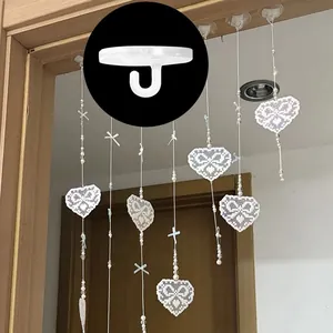 Gancio a J in plastica bianca con decorazioni a cuore in pizzo appese a una porta