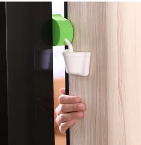 Close-up view of a green soft foam finger pinch guard protecting a child hand in a door gap