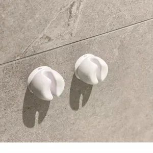 Close-up of white wall-mounted toothbrush holders on grey tile back