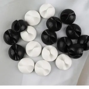 Vue macro d'organisateurs de câbles circulaires noirs et blancs sur fond de tissu gris