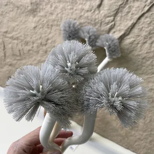 Close-up of multiple curved handle toilet brushes with dense grey round bristled heads