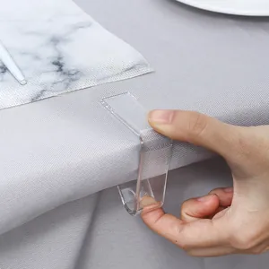 Clear acrylic tablecloth clip securing a grey woven table cover on a dining table