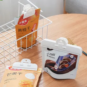 White plastic moisture-proof sealing clips for snack bags displayed on a wooden table.