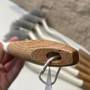 Detail of a Japanese-style toilet brush featuring a textured wooden handle with lanyard hole.