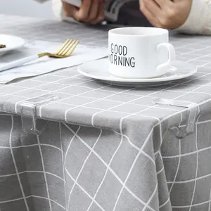 Transparent plastic tablecloth clips for table cover fixing on a grey grid dining table