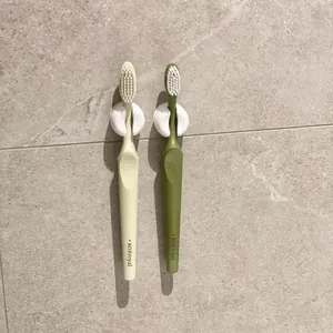 Minimalistische weiße Saugnapf-Zahnbürstenhalter an einer strukturierten Fliesenwand