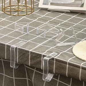 Set aus transparenten Tischdeckenklammern aus Kunststoff auf einem karierten Tisch