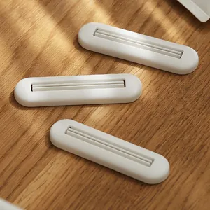 Three minimalist white manual toothpaste tube squeezers for facial cleanser on wood