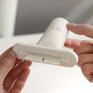 White manual tube squeezer for toothpaste and facial cleanser shown in hand demonstration