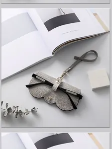 Étui à lunettes élégant en cuir gris avec lanière portable sur bureau minimaliste