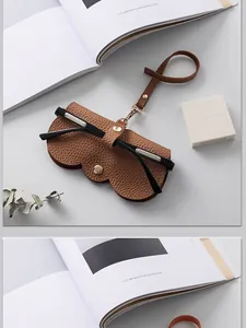 Gros plan sur l'étui à lunettes en cuir marron avec bouton pression et sangle