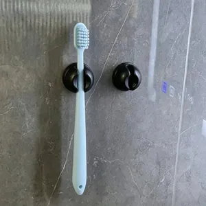 Close-up of black suction cup toothbrush holder mounted on a marble wall with toothbrush