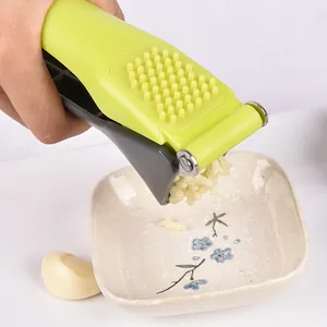 Ergonomische Knoblauchpresse aus grünem Kunststoff presst frischen Knoblauch in Schale