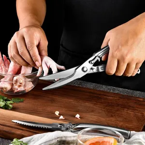 Heavy duty stainless steel kitchen shears cutting chicken bone on a wooden board