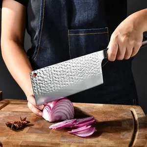 Forged Chinese chef knife with hammered finish cutting red onion on a wooden board