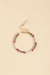 Detailed view of the faceted colorful crystal beads and gold-toned metal logo tag
