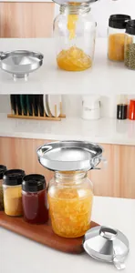 Detalle de embudos de acero inoxidable de boca ancha para envasar mermelada en cocina.