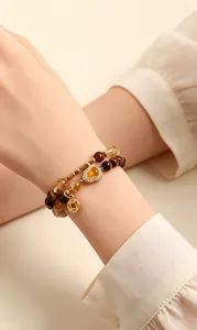 Close-up of yellow tiger eye and citrine double-strand bracelet with heart charm.